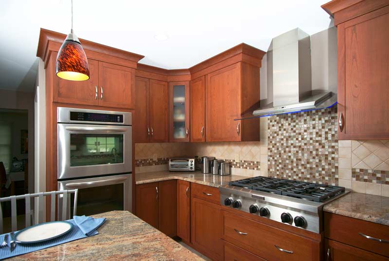 this open cherry kitchen has signature custom cabinetry in cherry stain with stainless steel appliances throughout
